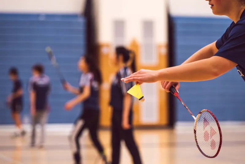 Joueuse au service lors d'une séance de badminton en gymnase