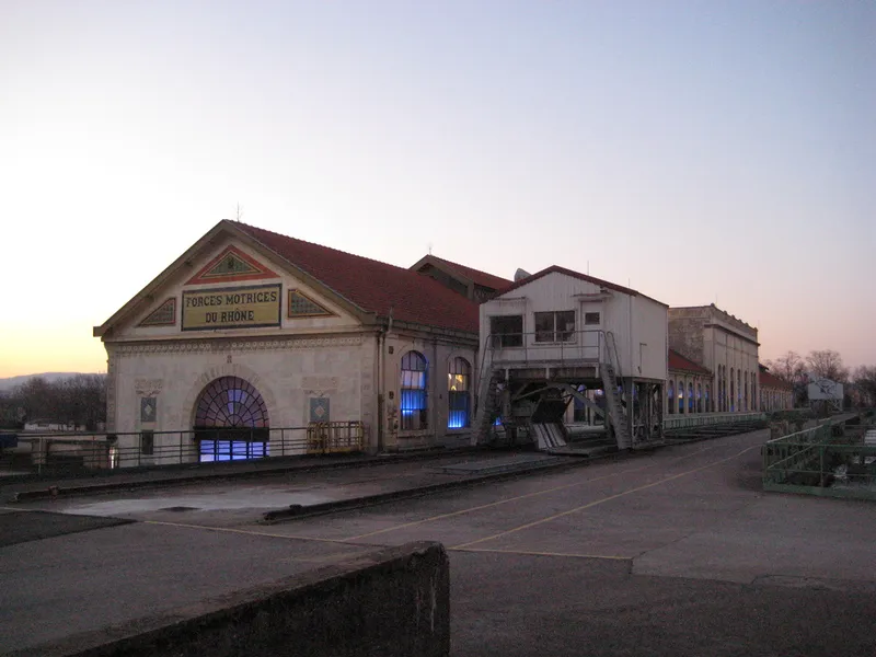 Façade de la centrale hydroélectrique de Cusset, portant l'inscription Forces motrices du Rhône, au crépuscule