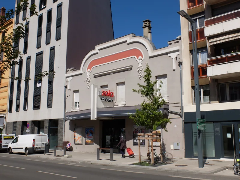 La façade du cinéma Le Zola sur le cours Émile-Zola à Villeurbanne, avec son fronton chantourné et son enseigne rouge