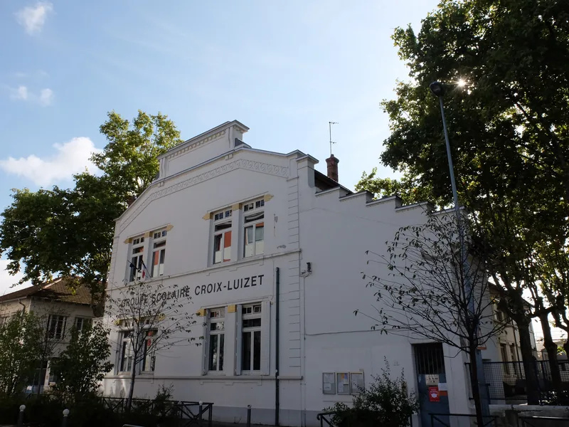 Façade blanche du groupe scolaire Croix-Luizet à Villeurbanne, avec son nom gravé sous le fronton